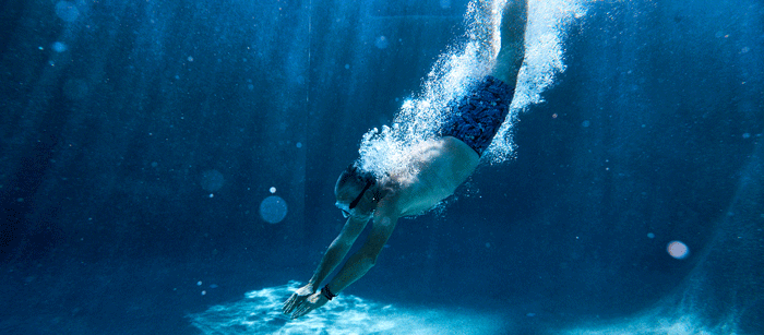 Underwater angle of man diving into a pool