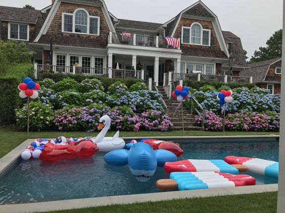 USA flags waving and red, white and blue floats and decorations in and around pool